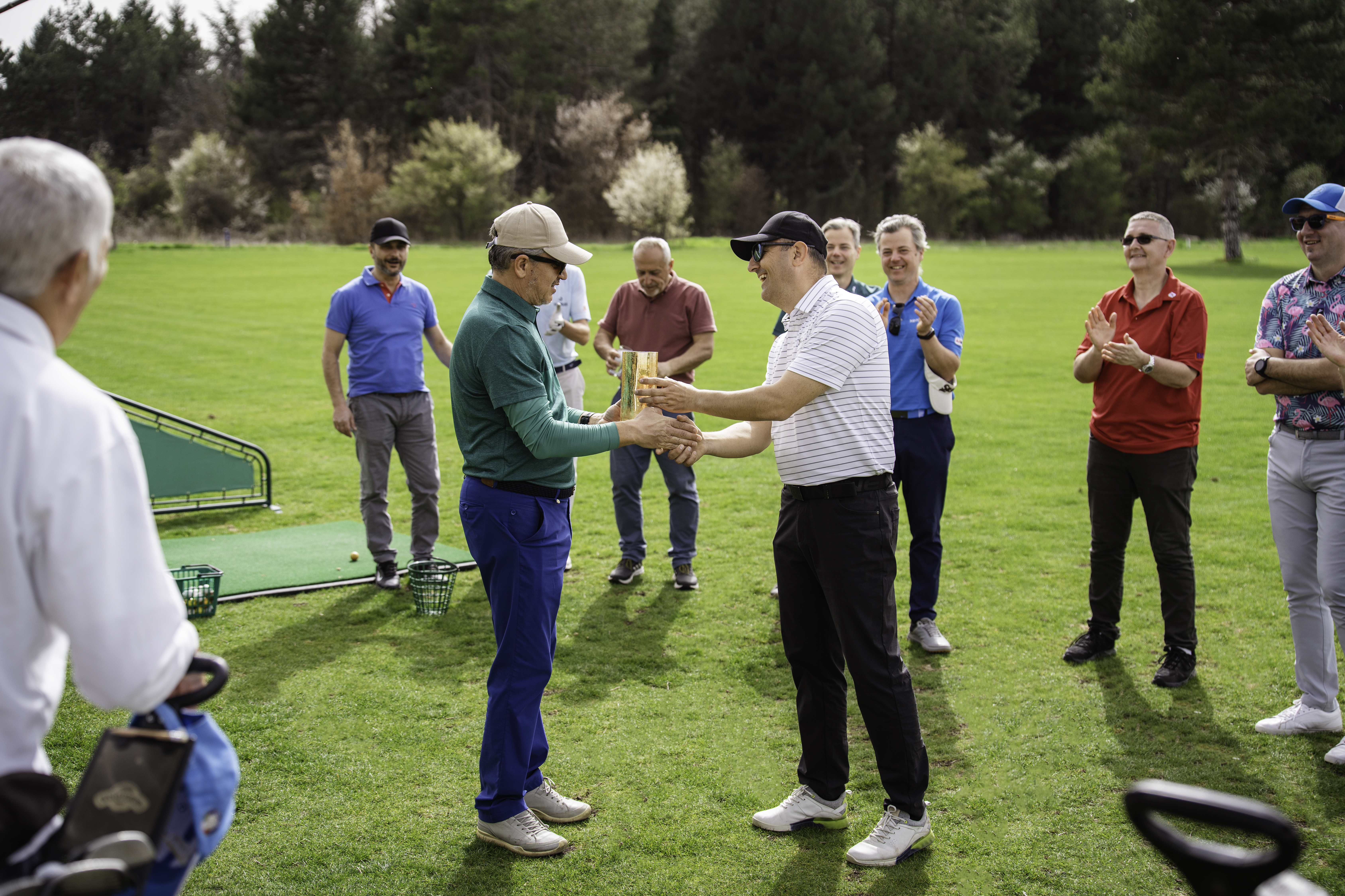 Two guys shaking hands on a putting green after a great game of golf.